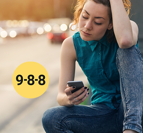 9-8-8 poster of a woman sitting by a road way holding her cell phone, looking worried.